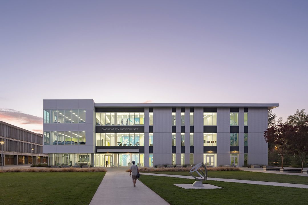 Image of the Diane Bryant STEM Innovation Center at dusk with the interior lit and the wall graphics visible on each floor