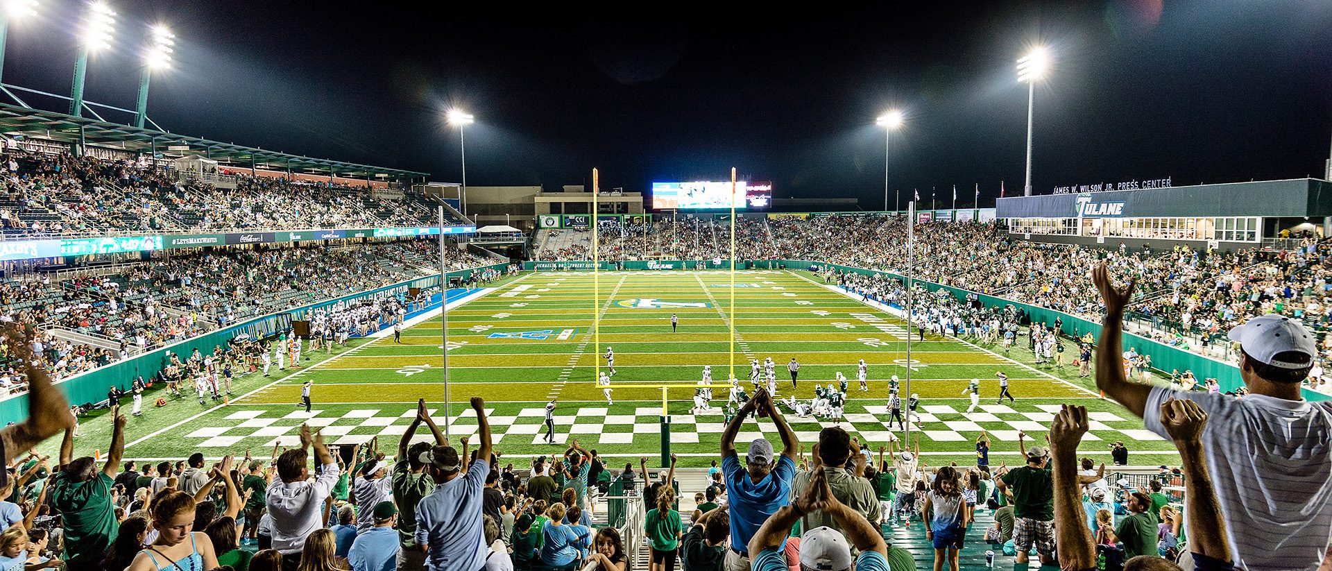 Image of fans cheering during a night football game at Tulane University Yulman Stadium