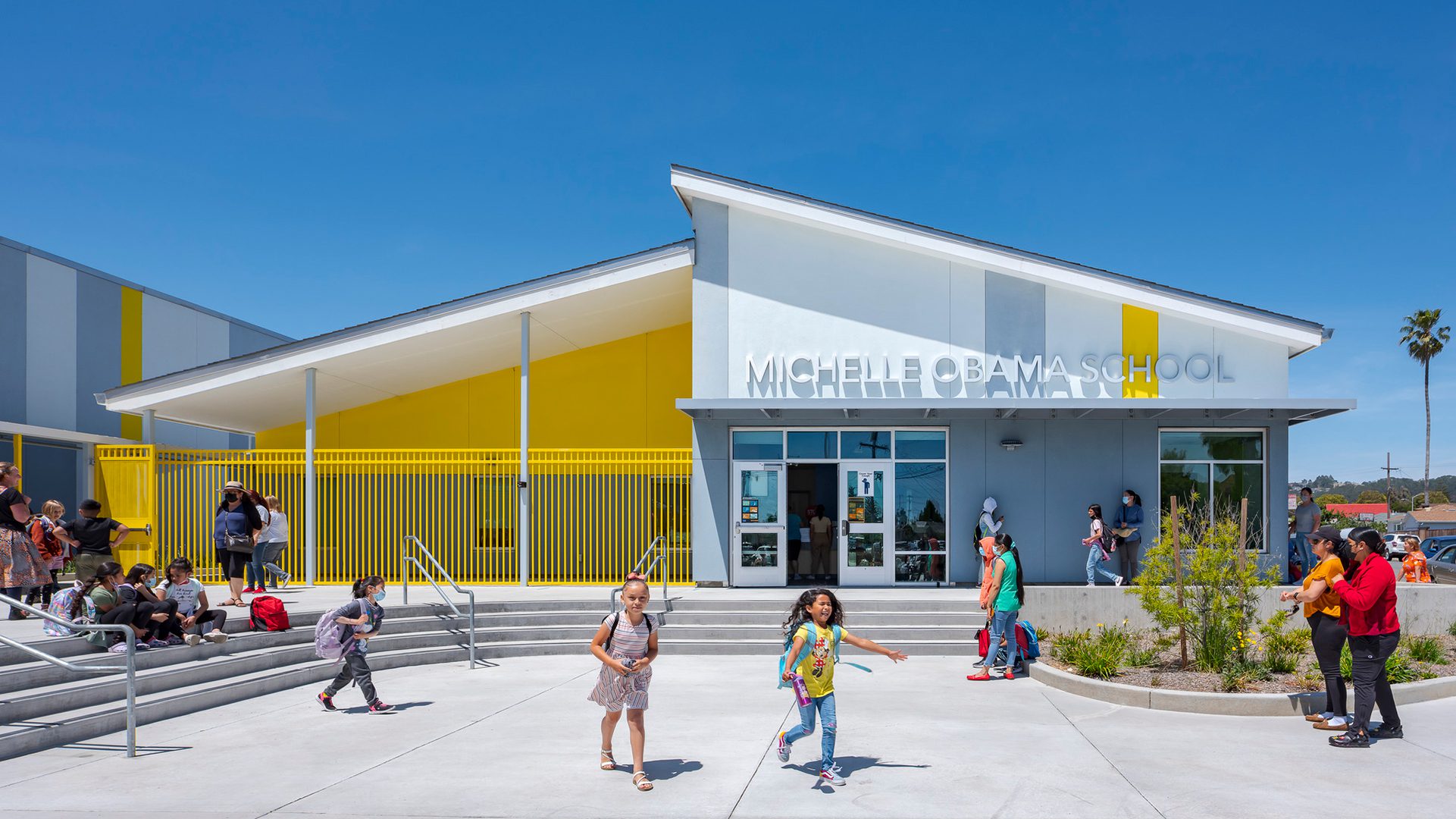 Image of exterior entry of Michelle Obama School with elementary students and parents/guardians