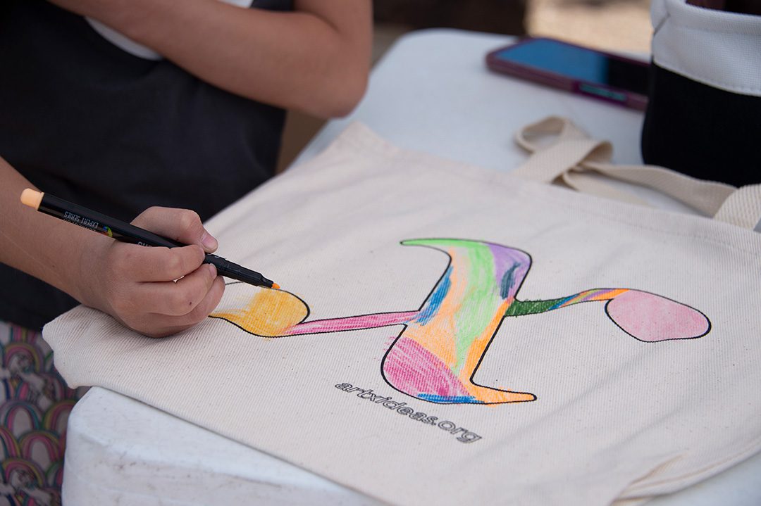Photo of event attendee coloring in an ARTx promotional tote bag.