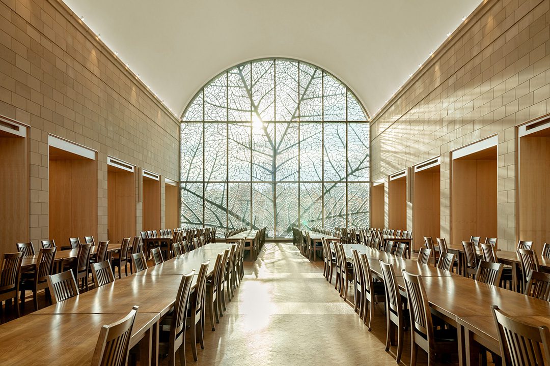 Photo of the interior of Patterson Hall showing the formal dining space with daylight streaming in from the large barrel-vaulted window feature.